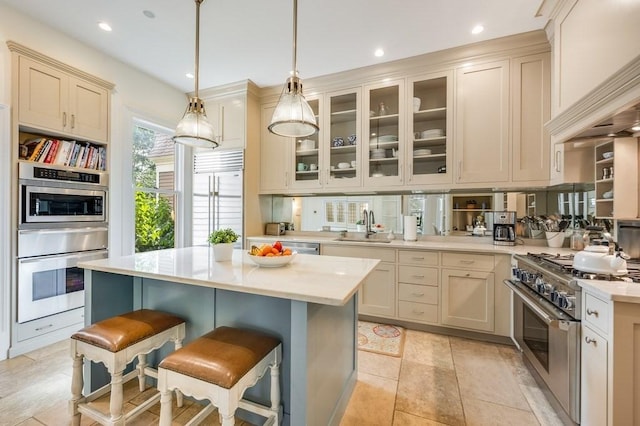 kitchen featuring sink, decorative light fixtures, cream cabinetry, a breakfast bar area, and high quality appliances