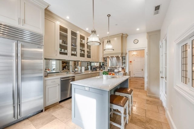 kitchen with pendant lighting, a breakfast bar area, light tile patterned floors, a kitchen island, and stainless steel appliances