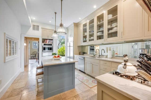 kitchen featuring dishwasher, a center island, sink, decorative light fixtures, and cream cabinetry