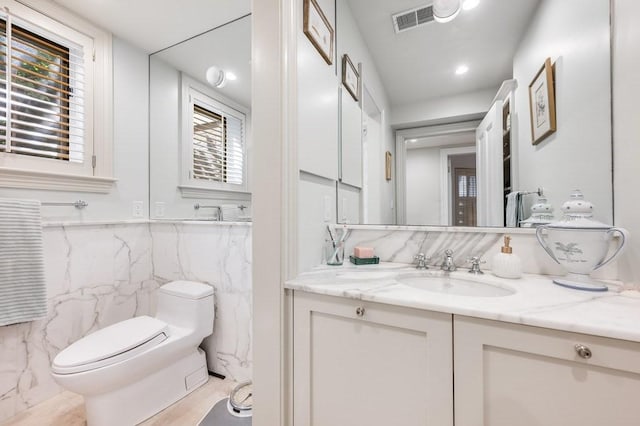 bathroom with vanity, tile walls, and toilet