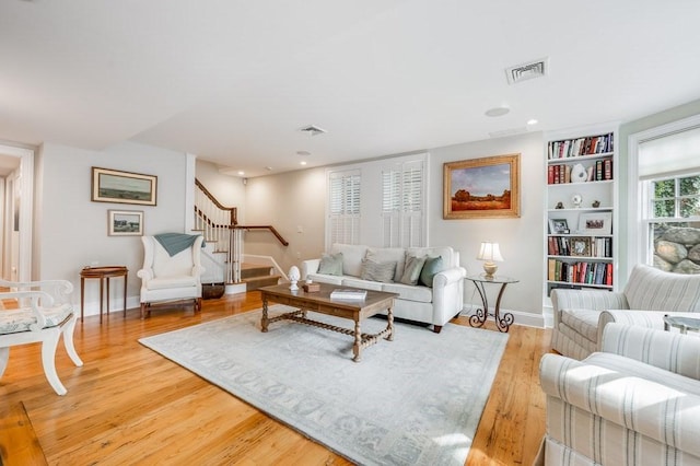 living room featuring built in features and light hardwood / wood-style flooring