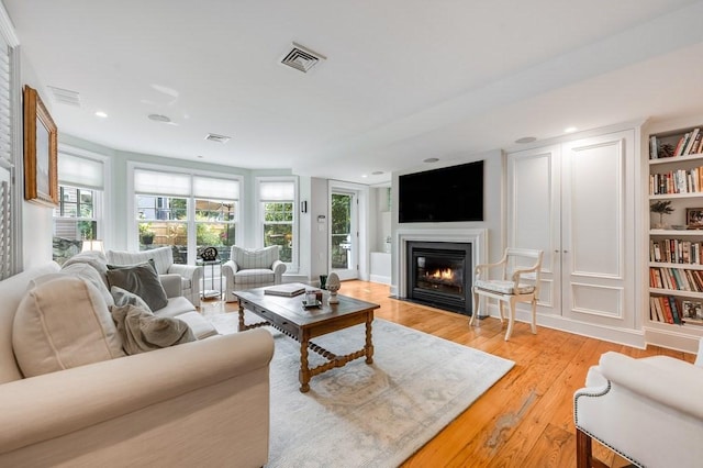 living room featuring built in shelves and light hardwood / wood-style flooring