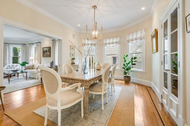 dining space featuring ornamental molding, light hardwood / wood-style floors, and a notable chandelier