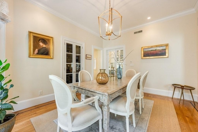 dining area with light hardwood / wood-style floors, crown molding, and a chandelier