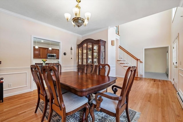 dining area with ornamental molding, light wood-type flooring, a chandelier, and baseboard heating