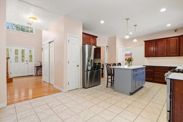 kitchen with a breakfast bar, decorative light fixtures, light tile patterned floors, a kitchen island, and stainless steel appliances