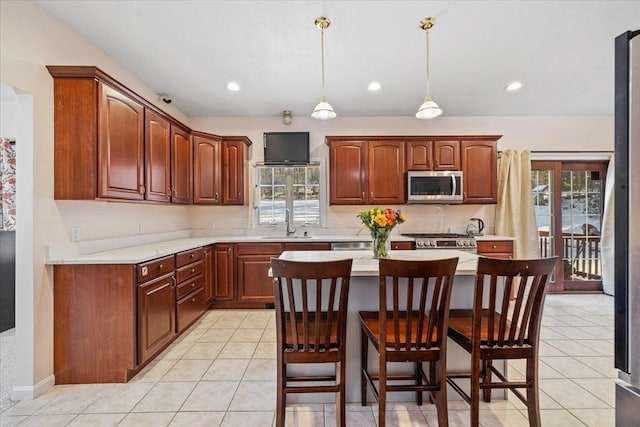 kitchen featuring a breakfast bar, stainless steel appliances, a center island, light tile patterned flooring, and decorative light fixtures