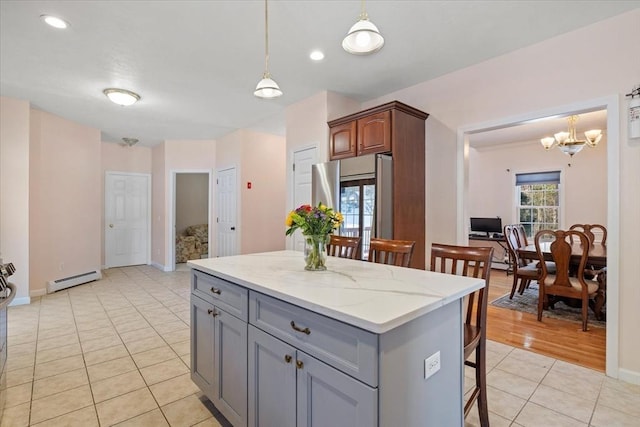 kitchen featuring decorative light fixtures, gray cabinets, stainless steel refrigerator, and a kitchen island