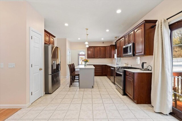 kitchen featuring sink, hanging light fixtures, a kitchen island, stainless steel appliances, and a kitchen bar