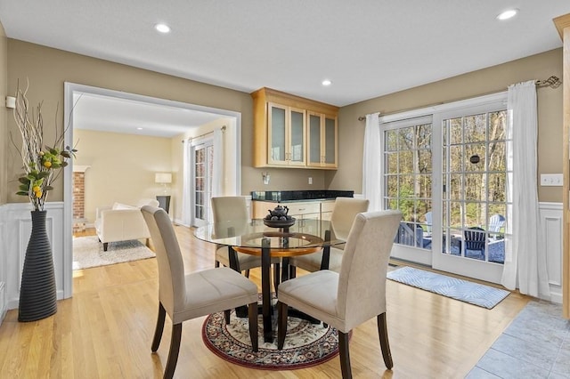 dining area with recessed lighting, a wainscoted wall, and light wood-type flooring