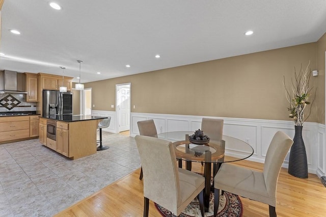 dining space with light tile patterned floors, a decorative wall, wainscoting, and recessed lighting