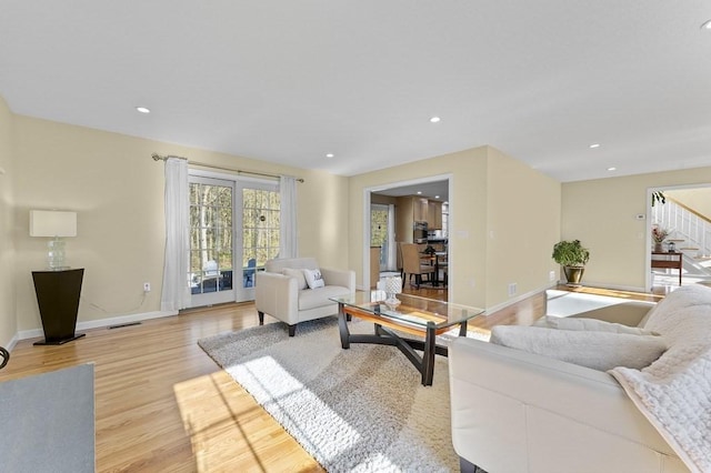 living area featuring visible vents, stairway, baseboards, recessed lighting, and light wood-style flooring