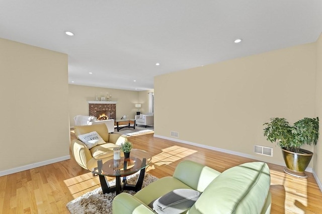 living room featuring visible vents, light wood finished floors, baseboards, and a fireplace