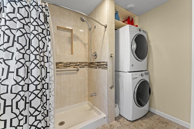 bathroom with baseboards, stacked washer and dryer, and a shower stall