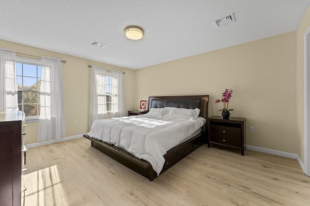 bedroom with baseboards, light wood-type flooring, and visible vents