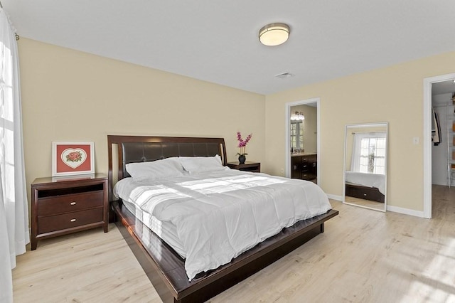 bedroom with visible vents, a closet, baseboards, a walk in closet, and light wood-style flooring