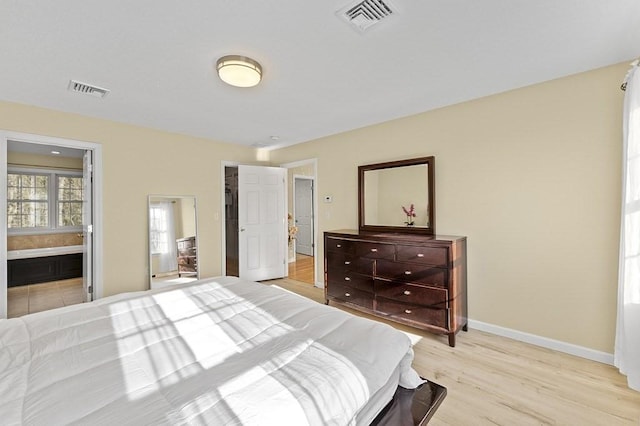 bedroom featuring visible vents, connected bathroom, light wood finished floors, and baseboards