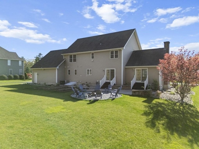 back of house featuring a yard, a patio, a chimney, and entry steps