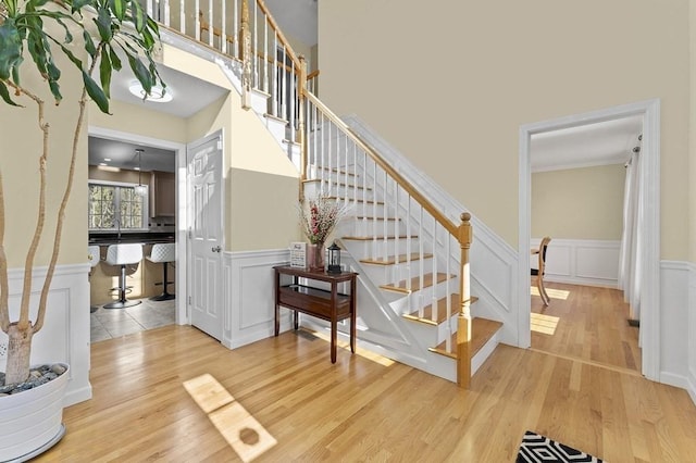 stairs featuring wainscoting, a decorative wall, and wood finished floors