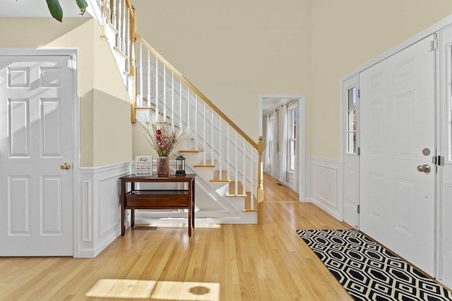 entrance foyer with wainscoting, wood finished floors, and stairway