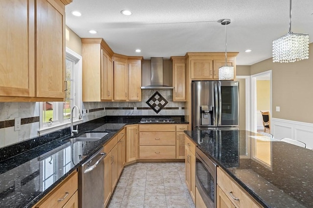 kitchen featuring a sink, appliances with stainless steel finishes, light brown cabinetry, and wall chimney exhaust hood