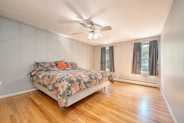 bedroom featuring baseboard heating, light wood finished floors, baseboards, and ceiling fan