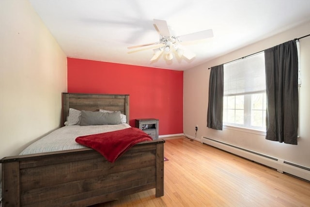 bedroom featuring a baseboard radiator, wood finished floors, ceiling fan, and baseboards