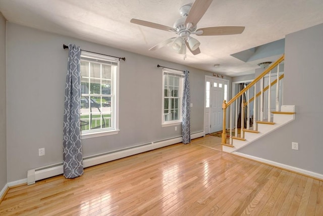 empty room with ceiling fan, hardwood / wood-style floors, stairs, and baseboards