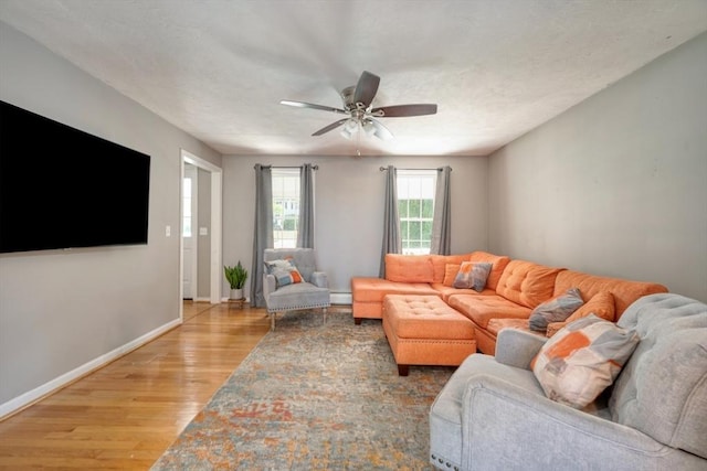 living area featuring light wood-style flooring, ceiling fan, baseboards, and a baseboard heating unit