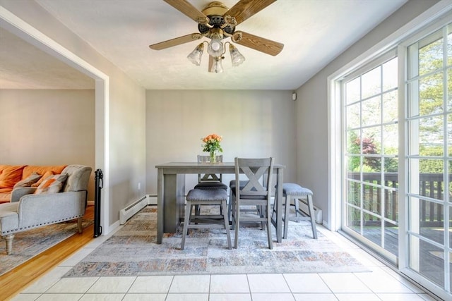 tiled dining space with a baseboard heating unit, plenty of natural light, and a ceiling fan