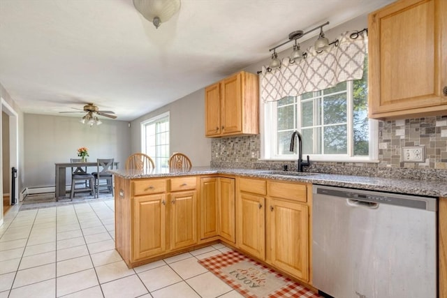 kitchen featuring stainless steel dishwasher, a sink, ceiling fan, a peninsula, and backsplash