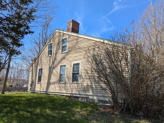 view of side of property with a yard and a chimney
