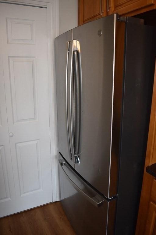 interior details featuring brown cabinetry, dark countertops, wood finished floors, and freestanding refrigerator