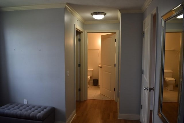 hallway featuring baseboards, wood finished floors, and crown molding