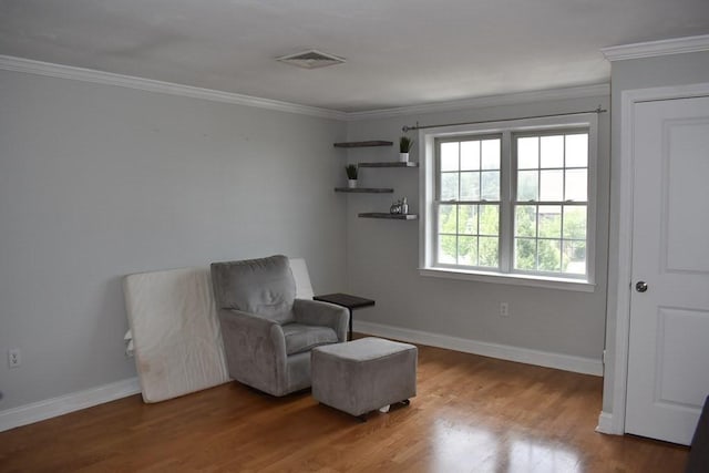 living area featuring crown molding, visible vents, and wood finished floors