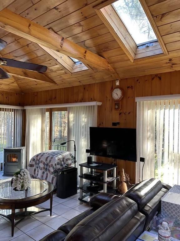 living room featuring a wealth of natural light, light tile patterned flooring, wooden ceiling, and lofted ceiling with skylight