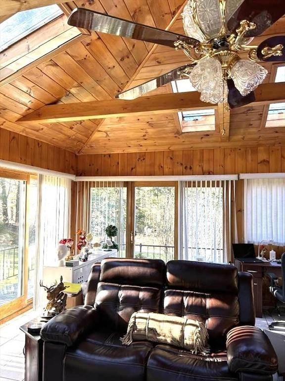 living room featuring high vaulted ceiling, wooden walls, a skylight, ceiling fan, and wood ceiling