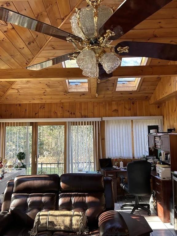 living room featuring wood walls, lofted ceiling with skylight, ceiling fan, light tile patterned flooring, and wood ceiling