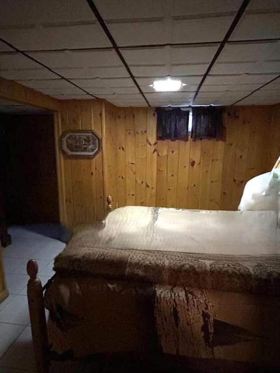 unfurnished bedroom featuring wooden walls and a drop ceiling