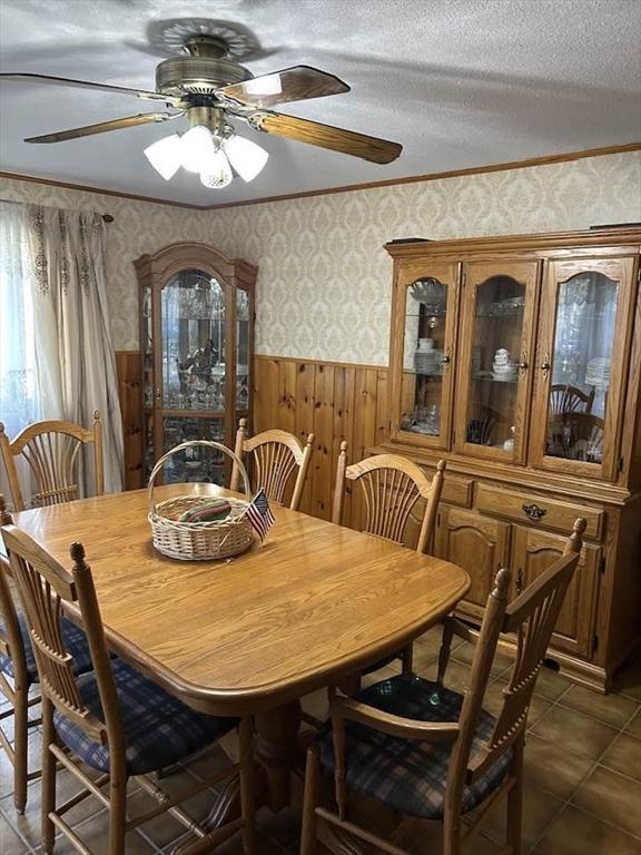 dining space featuring crown molding, ceiling fan, and wood walls