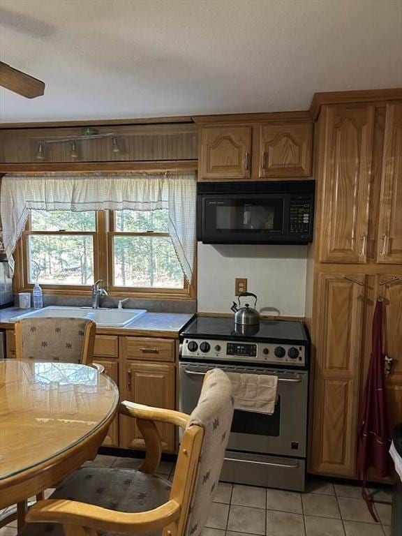 kitchen with ceiling fan, sink, stainless steel stove, and light tile patterned flooring