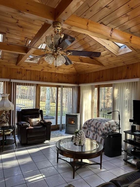 living room featuring vaulted ceiling with skylight, ceiling fan, wooden walls, and wood ceiling