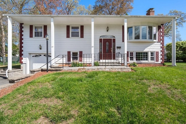 bi-level home featuring a front yard, a chimney, and a garage