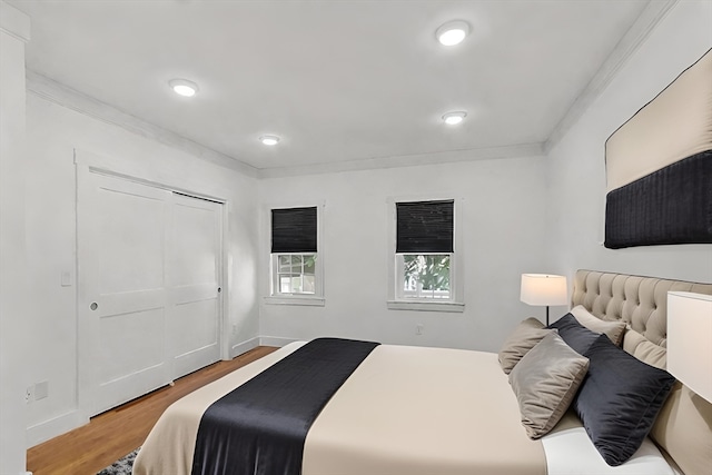 bedroom featuring a closet, wood-type flooring, and ornamental molding