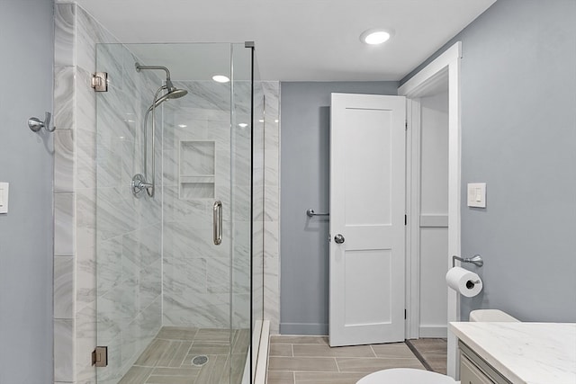 bathroom featuring vanity, toilet, and a shower with shower door