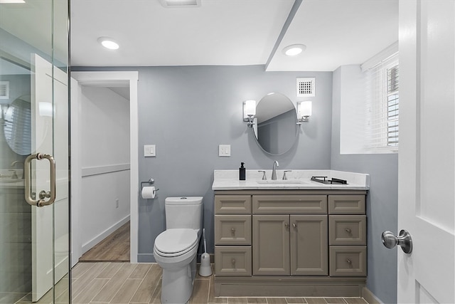 bathroom featuring walk in shower, vanity, and toilet