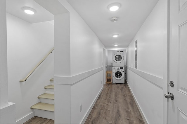 corridor with wood-type flooring and stacked washer / dryer