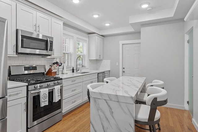 kitchen with light hardwood / wood-style flooring, white cabinets, sink, and stainless steel appliances