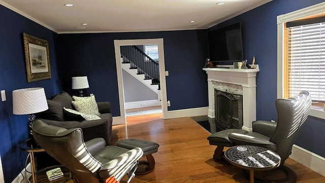 living room featuring hardwood / wood-style floors, crown molding, and a high end fireplace