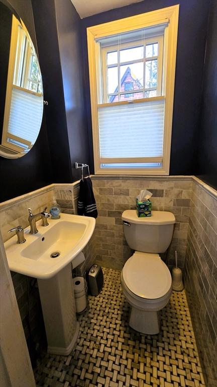 bathroom featuring toilet, tile patterned floors, tile walls, and plenty of natural light